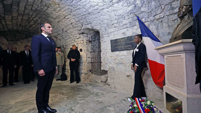 French President Emmanuel Macron (L) pays tribute in front of a statue of Toussaint Louverture, leader of the Haitian independence movement, before visiting the "Chateau de Joux" during a ceremony marking the 175th anniversary of the abolition of slavery in France, in La Cluze-et-Mijoux, near Besancon, eastern France, on April 27, 2023. - Macron visited "Chateau de Joux" to pay tribute to mark the 220th anniversary of the death of Franco-Haitian general Toussaint Louverture at the site where he was imprisoned until his death. (Photo by Christophe PETIT TESSON / POOL / AFP)