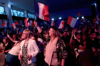 Supporters of Marine Le Pen, French far-right leader and far-right Rassemblement National (National Rally - RN) party candidate, hold French flags at the venue for Marine Le Pen's reaction speech before partial results in the first round of the early French parliamentary elections, in Henin-Beaumont, France, June 30, 2024. REUTERS/Yves Herman