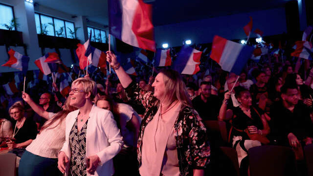 Supporters of Marine Le Pen, French far-right leader and far-right Rassemblement National (National Rally - RN) party candidate, hold French flags at the venue for Marine Le Pen's reaction speech before partial results in the first round of the early French parliamentary elections, in Henin-Beaumont, France, June 30, 2024. REUTERS/Yves Herman